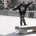 Skater in the black Shredding Rat Crewneck grinding a stone ledge