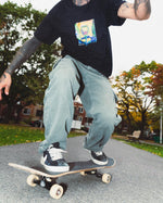 Skater landing a trick in the black Vineyard Vibes Graphic Tee